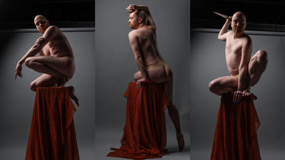 Three-panel studio photograph of a nonbinary model posed on draped red fabric pedestals against a dark gray backdrop, with dramatic spotlighting and no visible product branding.